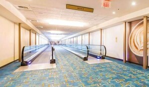 A hotel corridor with a blue patterned carpet, glass railings, and a sign indicating the direction to the MGM.
