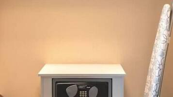 A white bedside table with a radio, a drawer, and a curtain on the right.