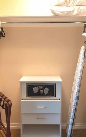 A white bedside table with a radio, a drawer, and a curtain on the right.