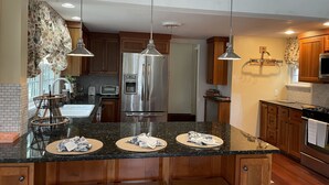 A modern kitchen with a stainless steel refrigerator, double sink, and wooden cabinets. - Large Charming Historic House close to Beaches (Clinton)