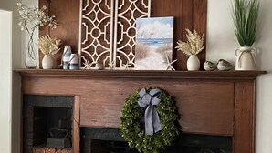 A fireplace with a decorative mantle, a wooden screen, and a wreath. - Large Charming Historic House close to Beaches (Clinton)