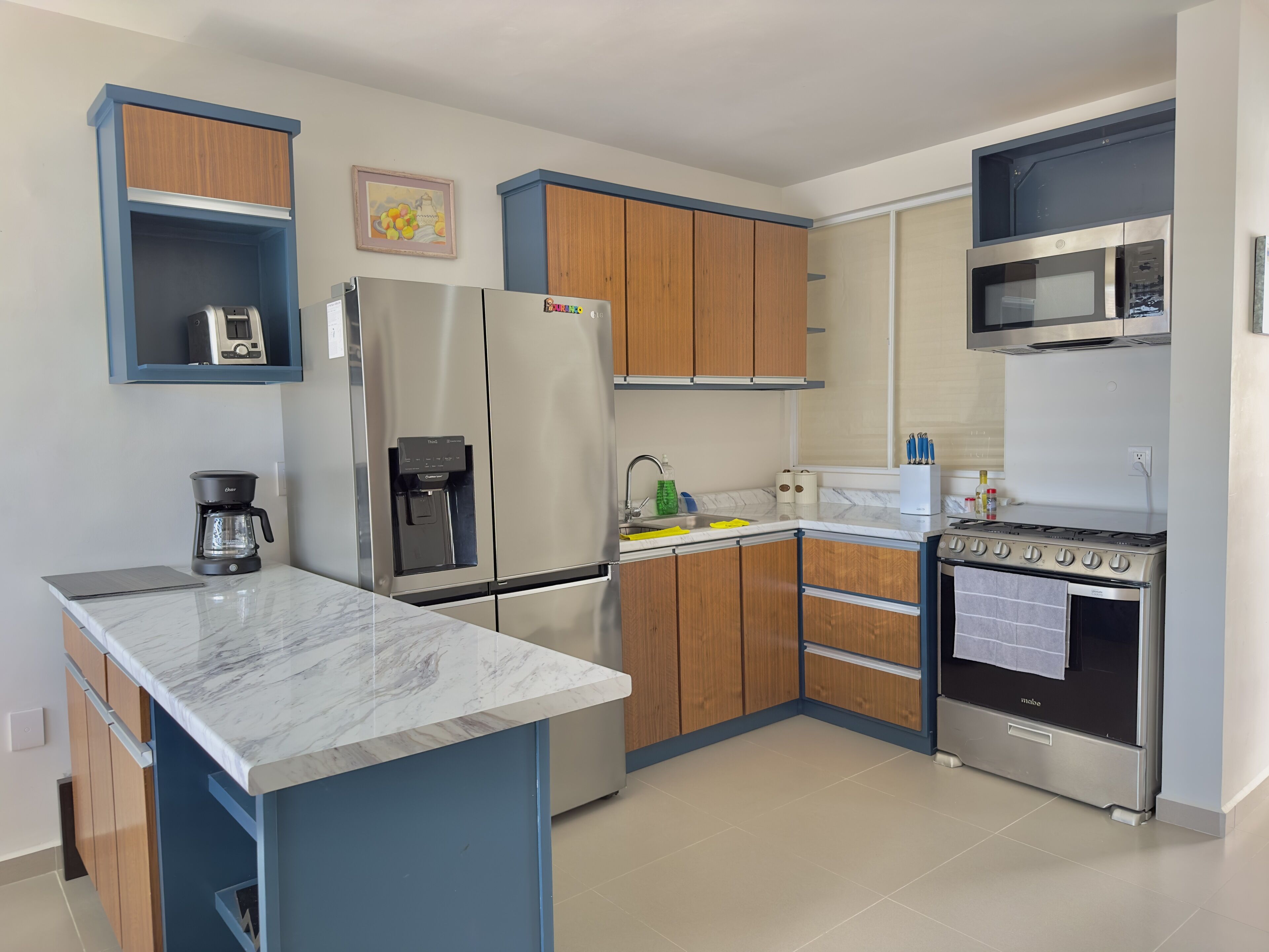 A modern kitchen with a marble countertop, stainless steel appliances, wooden cabinets, and a built-in oven.