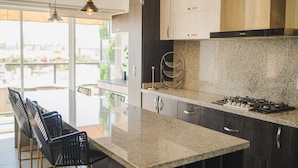 Una cocina moderna con una isla grande, armarios oscuros e iluminación colgante.