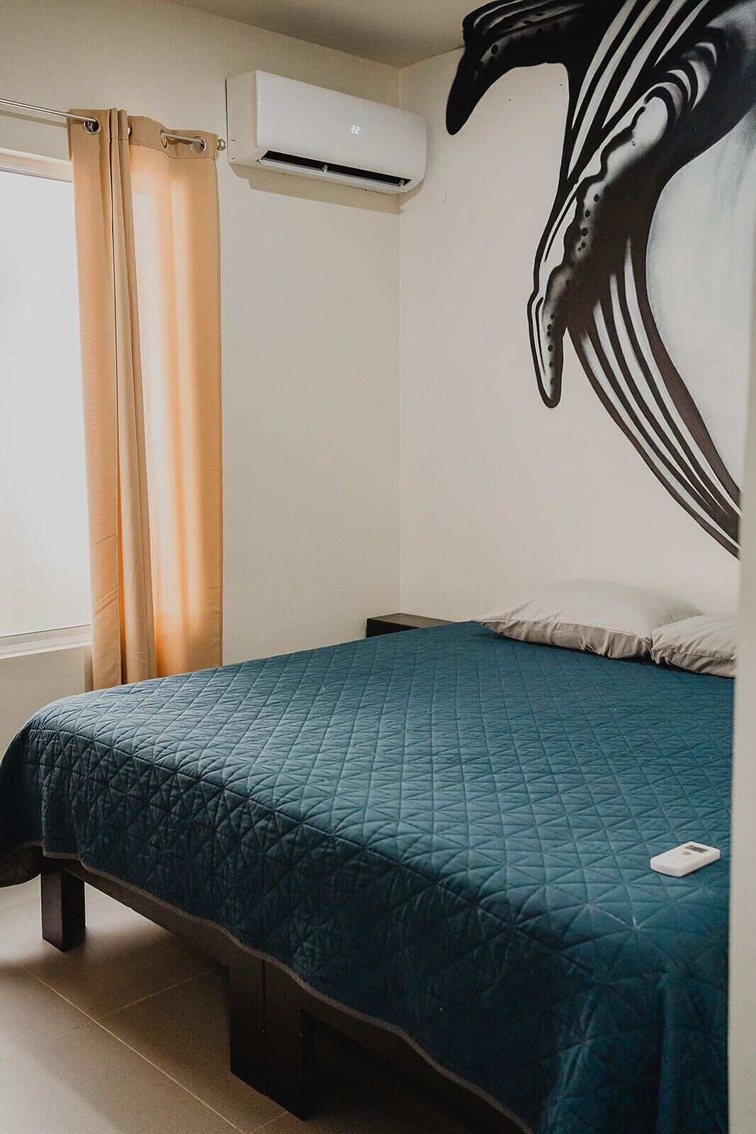Ein Schlafzimmer mit Bett, Vorhängen, einer Klimaanlage und Wanddekoration.