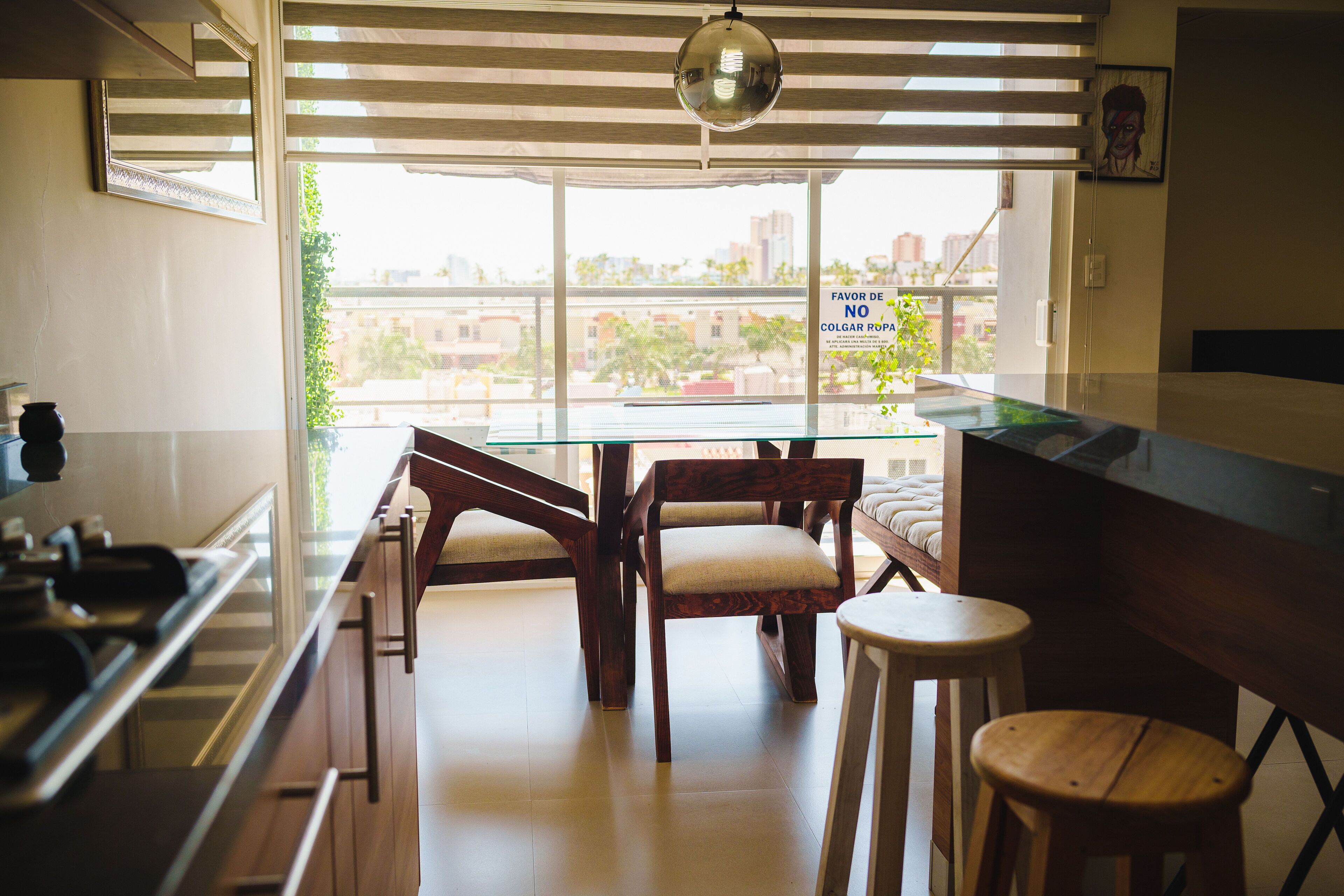 A kitchen with a glass table, wooden chairs, and a bar counter.
