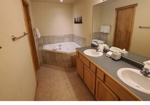Bathroom features a large bathtub, two sinks, and a large mirror.