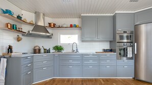 Una cocina moderna con gabinetes grises, un refrigerador de acero inoxidable y piso de madera.