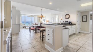 A spacious kitchen with a large island, a dining area with a view, and a chandelier. - Beachfront - Sugar white sand right at your doorstep (Navarre)