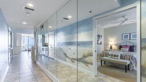 A hallway with a view into a bedroom featuring a bed, a bench, and a ceiling fan. - Beachfront - Sugar white sand right at your doorstep (Navarre)