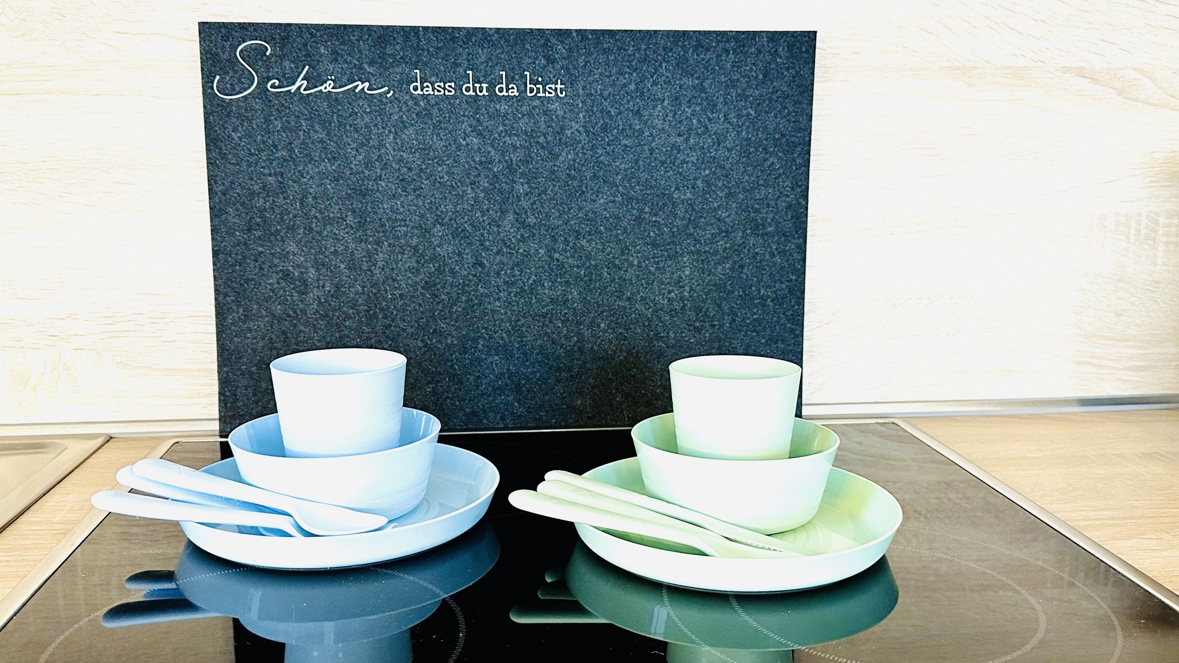 A table with a set of white and green bowls, plates, and chopsticks.