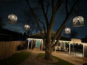 A tree in a backyard with hanging light fixtures. - Halloween Haunting Riverwalk ⛳️  Golf nearby,Cornhole, Lifesize CheckersFoosball (San Antonio)