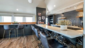 A modern kitchen with a bar area, bar stools, and a large window.