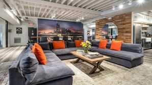 A modern lounge area with a sectional sofa, a coffee table, and a cityscape mural on the wall.
