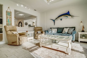 A living room with a beige leather armchair, a blue sofa, and a white coffee table.