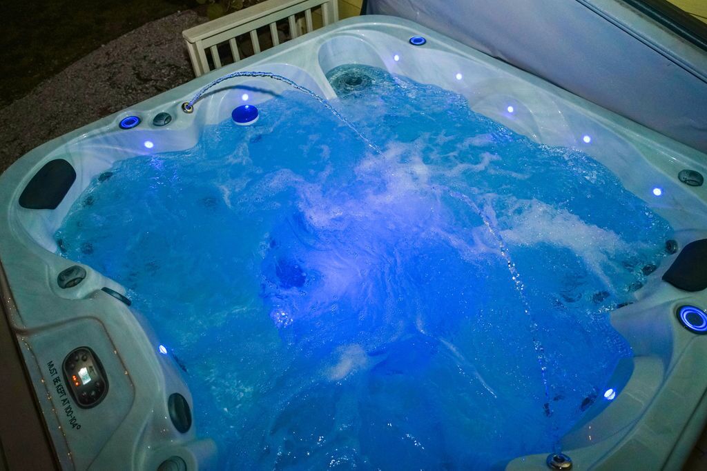Un bain à remous doté de plusieurs jets, d’un panneau de commande et d’éclairage à LED.