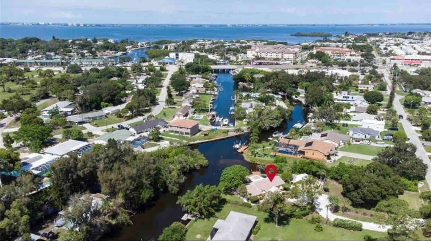 An aerial view of a residential area with houses, a river, and a marina.