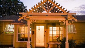 A yellow building with a wooden pergola entrance, a bench, and a gravel driveway. - Manatee Cove: Private Oasis with Wildlife, Hot Tub & Fun Game Room! (Bradenton)