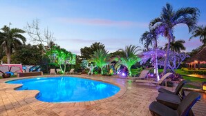 A swimming pool with a brick deck, surrounded by lounge chairs and palm trees. - Huge Ultra Estate on an Acre! Night Club, Gameroom, Hot-Tub. Pool, Tiki (North Miami Beach)