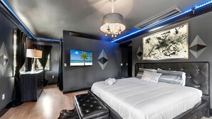 A modern bedroom with a large bed, a flat-screen TV, and a chandelier. - Huge Ultra Estate on an Acre! Night Club, Gameroom, Hot-Tub. Pool, Tiki (North Miami Beach)