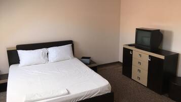 A hotel room with a bed, a TV on a cabinet, and a small table.