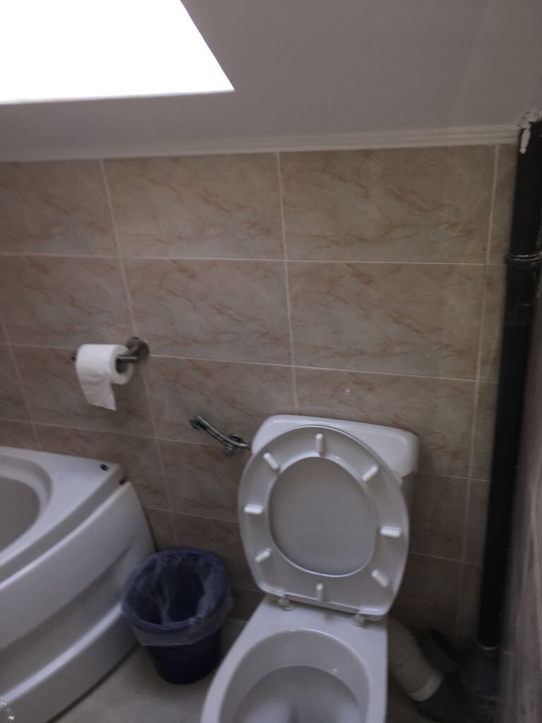 A bathroom with a toilet, a bidet, and a trash bin.