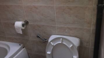 A bathroom with a toilet, a bidet, and a trash bin.