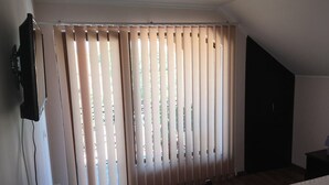 A bedroom with a bed, a radiator, and a window with blinds. - Step Inn (Alba Iulia)