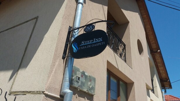 A hotel sign with the name "STEP INN CASA DE OASPETI" and a decorative emblem. - Step Inn (Alba Iulia)