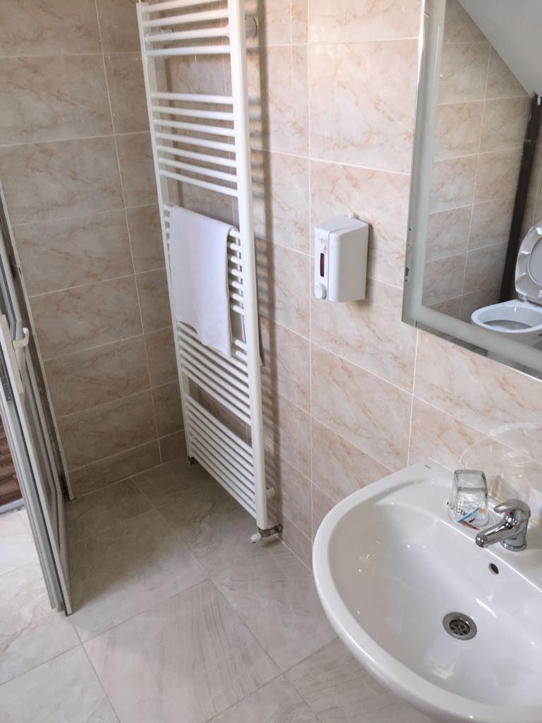 Un baño con un lavamanos blanco, un perchero y un espejo.
