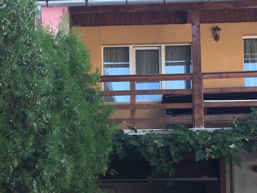Edifici amb un balcó, una finestra amb cortines i un lluminària penjada a la paret.