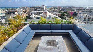 A rooftop terrace with a built-in seating area and a view of the cityscape and ocean.
