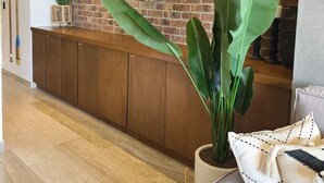 A reception area with a brick wall, a wooden reception desk, a large mirror, and a potted plant.