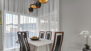 Enjoy meals in this elegant dining area with a table set for four, featuring a bowl of fresh fruit and a potted orchid.