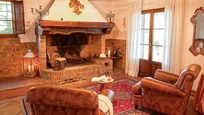 A cozy living room with a stone fireplace, leather armchairs, and a red patterned rug. - VILLA BELLAVISTA-TUSCANY-POOL -JACUZZI- breath-taking view-great for family (Toscana)