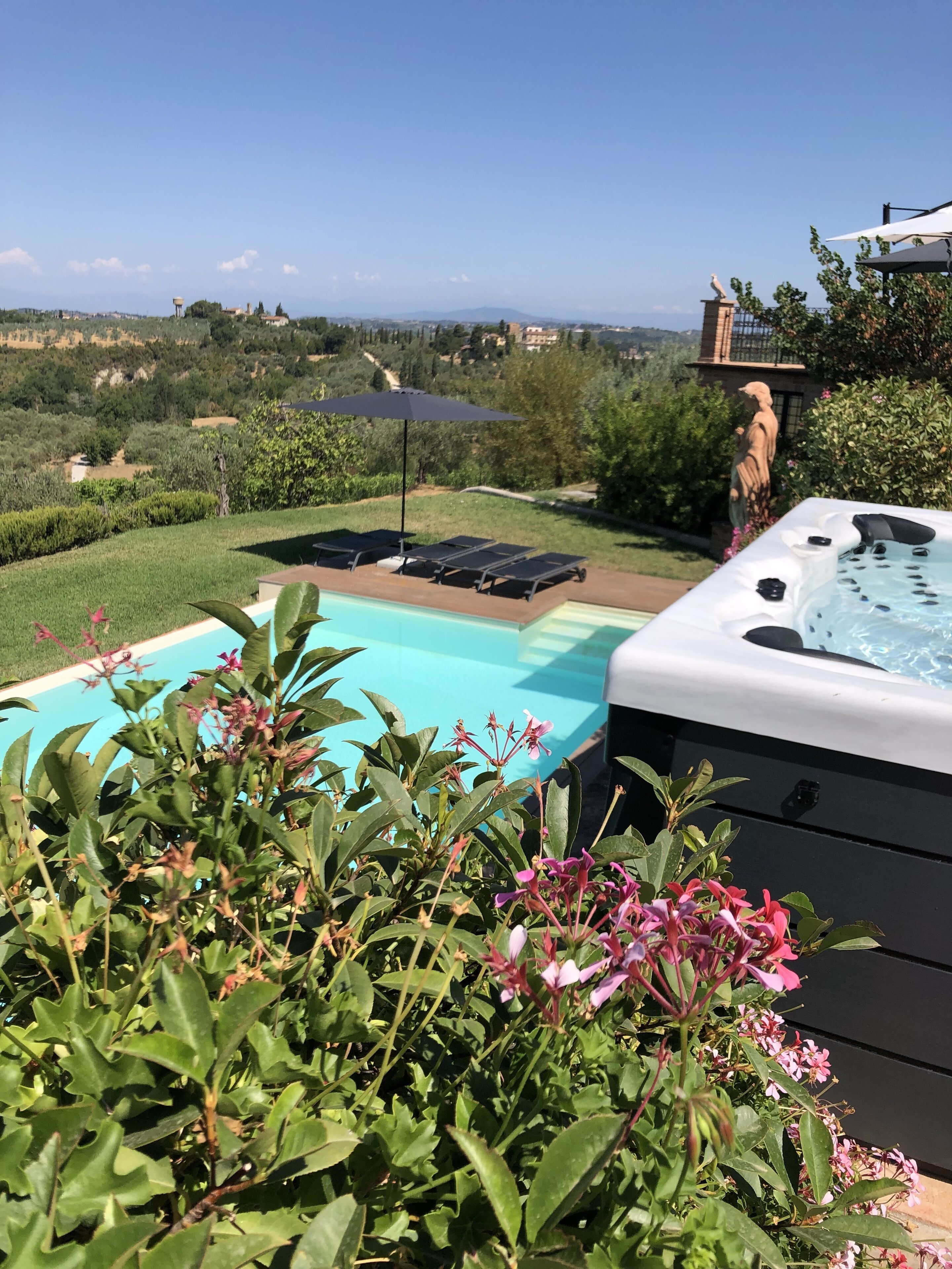 Tinaco con piscina y sillas de descanso, rodeado de follaje y una vista panorámica.