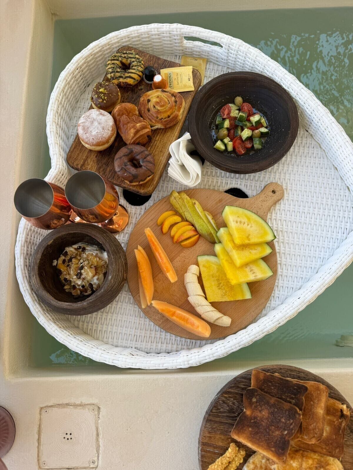 A breakfast tray with pastries, fruit, yogurt, and toast.