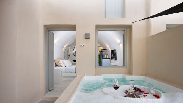 Zona de spa con un jacuzzi, una copa de vino tinto y una cesta de frutas.