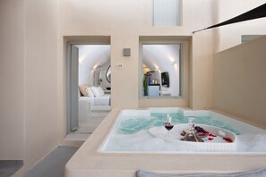 A spa area with a hot tub, a glass of red wine, and a basket of fruits.