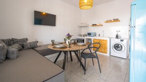 Una cocina moderna con comedor, lavadora y televisor montado en la pared.