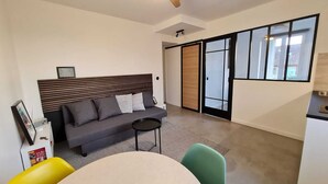 A modern living room with a sofa, a small round table, and a green chair. There is a sliding glass door leading to a balcony. - Le repaire de Barbizon (Barbizon)