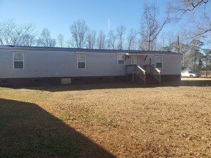 A single-story mobile home with a front porch and a small staircase leading to the entrance. - Cozy stay in a quiet area. (Jacksonville)