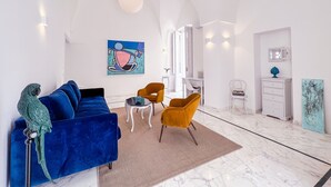 Una sala moderna con un sofá azul, un sillón amarillo y un loro en un perchero.