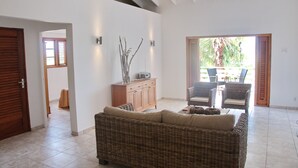 Una sala de estar con un sofá de mimbre, un mueble de madera y un comedor con sillas y una mesa.