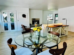 Una sala de estar moderna con una mesa de comedor de vidrio, sillas de madera, un sofá y una chimenea.
