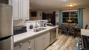 A kitchen with a stainless steel refrigerator, a double sink, and a dining area with a table and chairs. - Family & Pet Friendly Smart Home, Garage Parking, Fenced Yard, Near Stadiums (Euless)