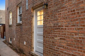 Traditional brick building with a white door and rectangular windows.