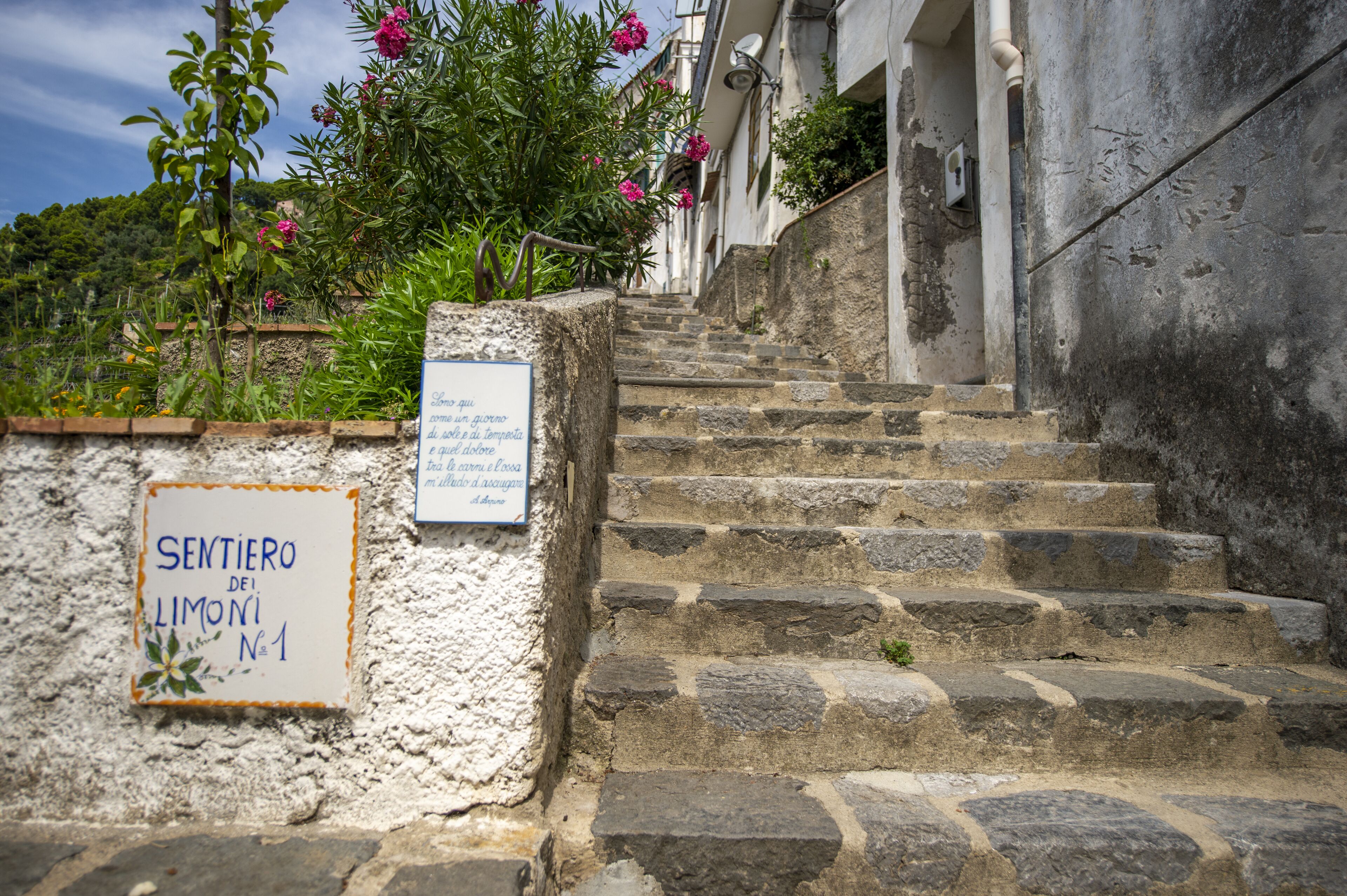 Un escalier en pierre mène à un bâtiment sur lequel est apposée une plaque indiquant « Sentiero dei Limoni N°1 ».