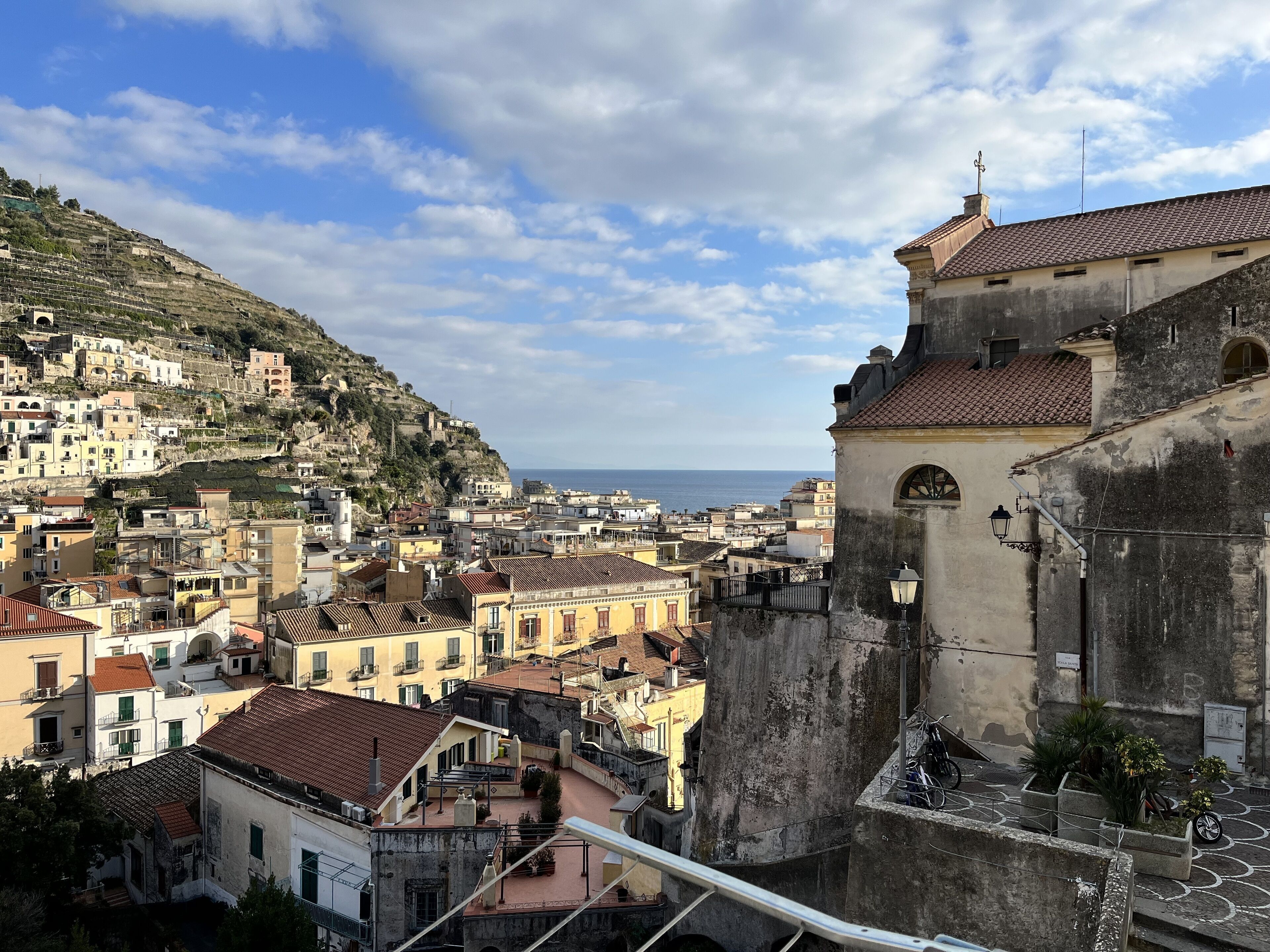 Une ville côtière avec des bâtiments à étages, une église imposante et une vue sur la mer.