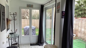 A room with a glass door leading to a backyard, a bench, a drum, and a coat rack.