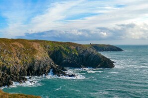 A coastal landscape with rocky cliffs and a small building on the horizon. - 5-star rural escape hidden between the coastal towns of Kinsale and Clonakilty, (Clonakilty)